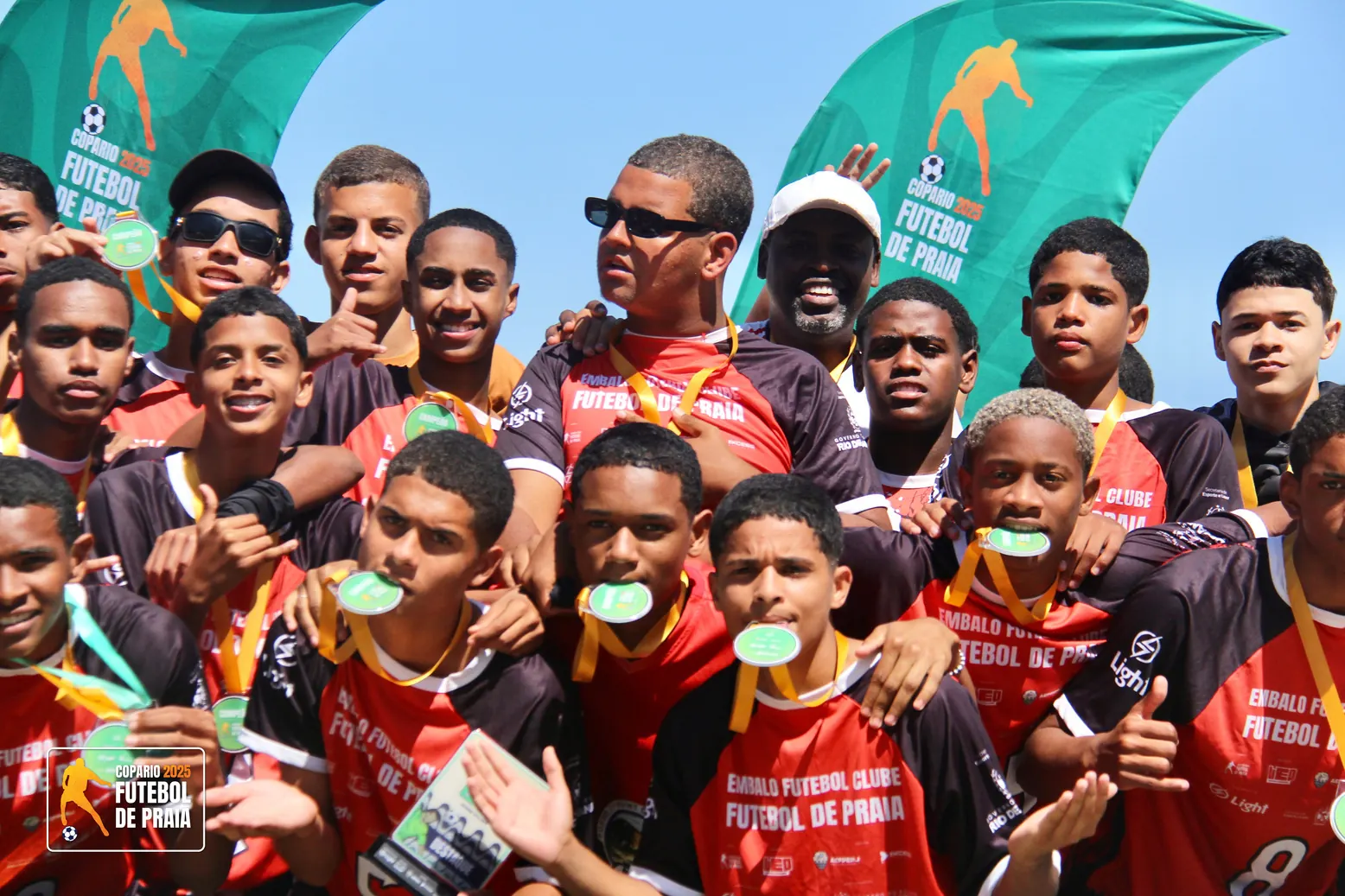 Meninos comemoram com as medalhas na boca depois de receber a premiação