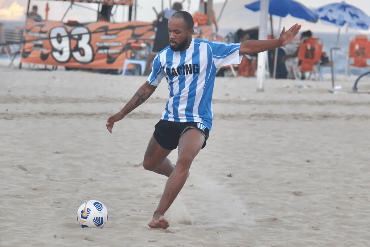 Jogador de camisa listrada de azul e branco chuta a bola