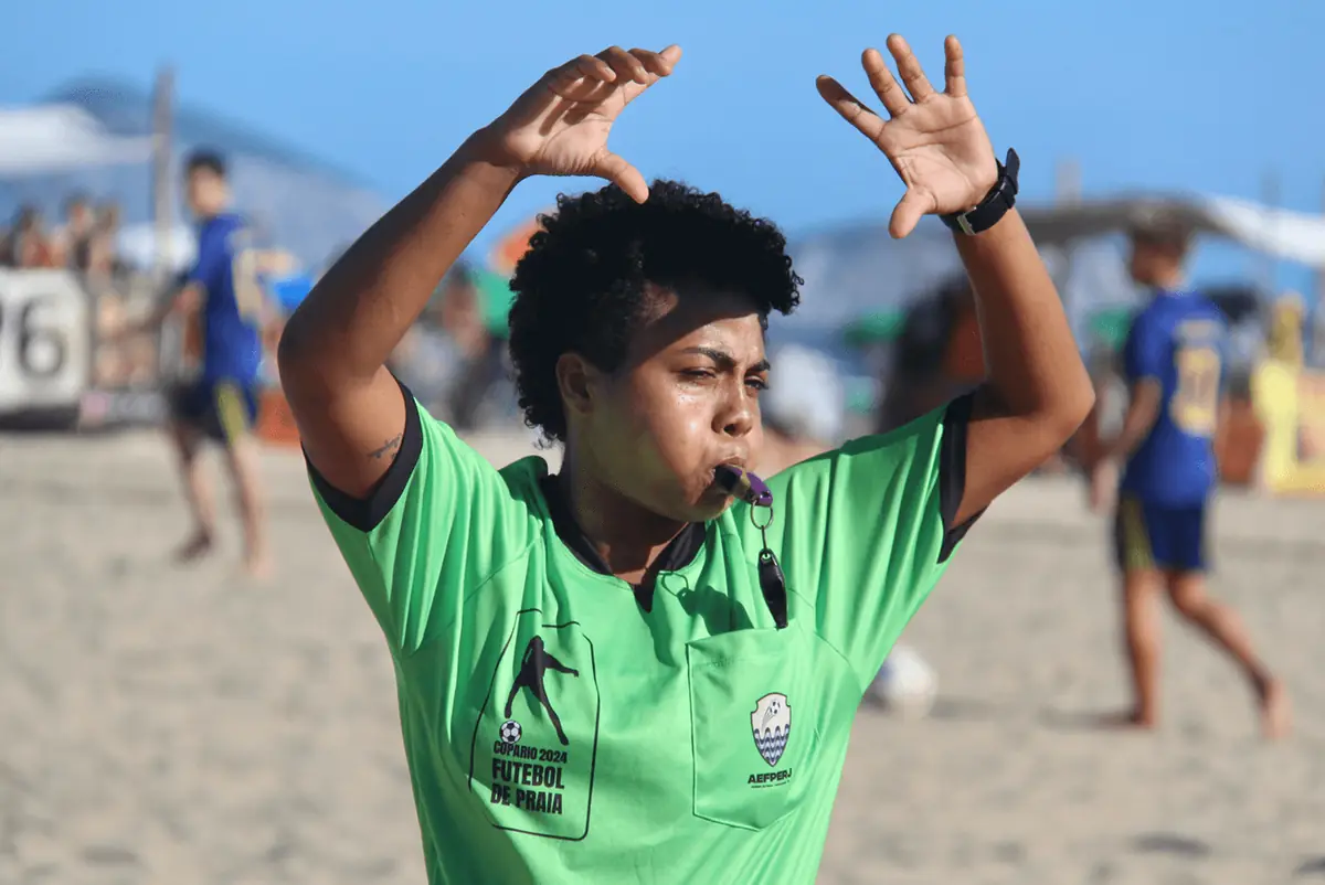 Árbitro de camisa verde gesticula durante a partida