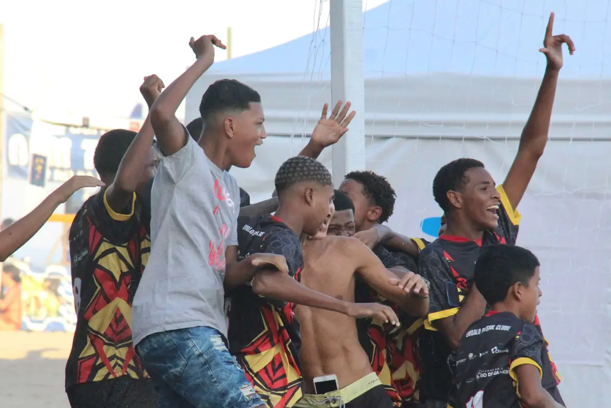 Jogadores comemoram um gol abraçados na areia