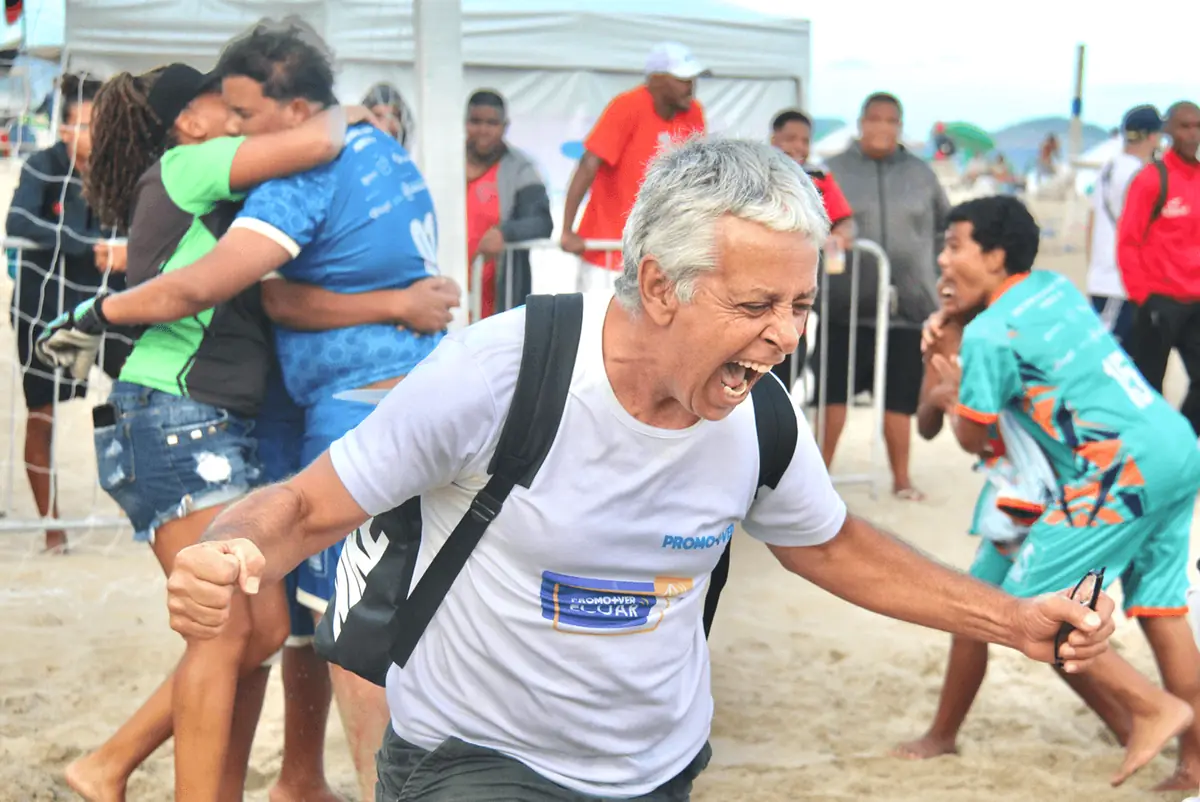 Homem de camisa branca abraça jogadores de camisa turquesa