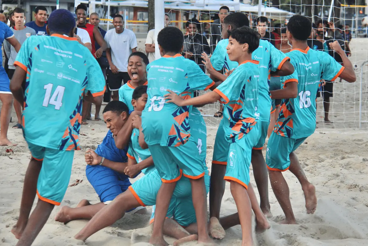 Time de camisa turquesa comemora amontoado na areia