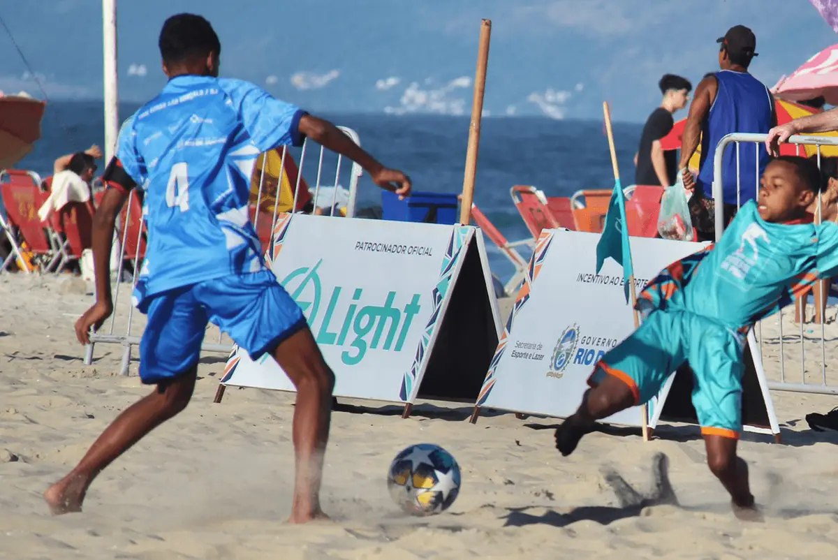Jogadores de camisa azul e turquesa disputam a bola diante do painel da Light