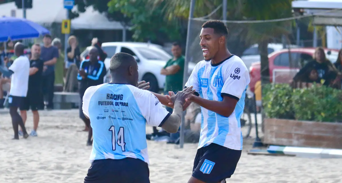 Dois jogadores de camisa azul e branca comemoram na areia