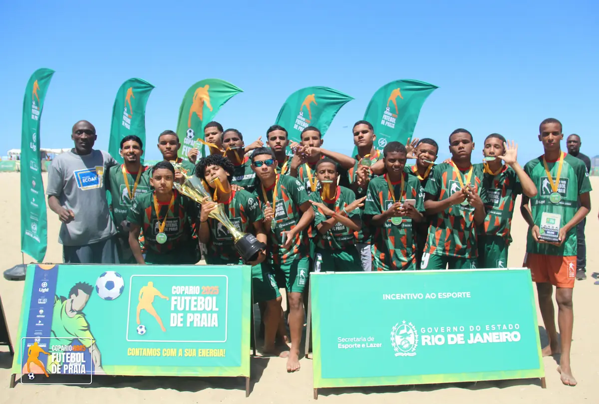 Time de camisa verde posa com medalhas diante do painel de incentivo ao esporte