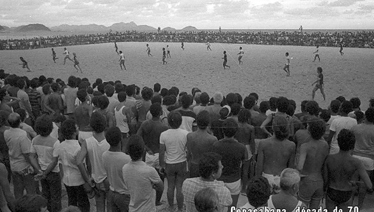 Foto em preto e branco de multidão em volta do campo de areia em Copacabana, na década de 70